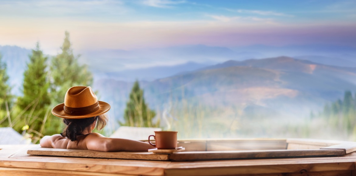 Woman sitting in hot tub outside with a mountain view | Watershed Cabins Bryson City Vacation Rentals